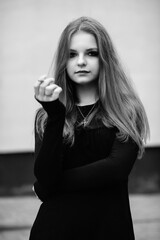 Portrait of a young beautiful long-haired girl in a dark dress in an urban environment. Black and white photo.