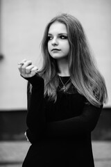 Portrait of a young beautiful long-haired girl in a dark dress in an urban environment. Black and white photo.