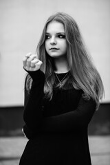Portrait of a young beautiful long-haired girl in a dark dress in an urban environment. Black and white photo.