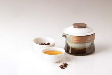 Crystal teapot and white bowl cup with herbal tea at white background, minimalist style menu, ads, product card