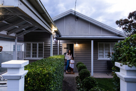 A mother and daughter at the front door of their neat timber house