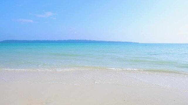 Pristine Coastal Scene with Rolling Waves on White Sand Beach and bright blue sky