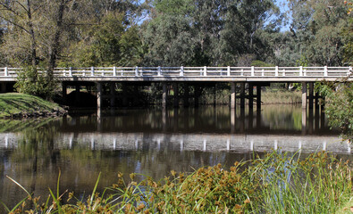 White bridge spanning a calm river surrounded by trees