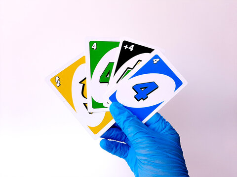 A hand with blue latex glove hold some uno card. Isolated on a white background. Semarang, Indonesia, August 30th 2020