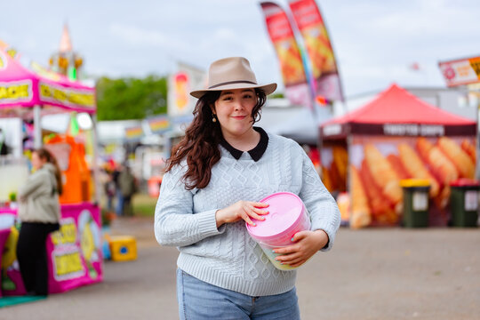 Young lady at rural agricultural show holding bucket of fairy floss in sideshow alley