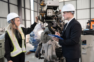 Fototapeta premium Business Caucasian male and female checking a robot arm with a clipboard 