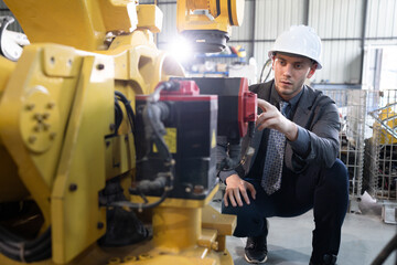 Business or engineer Caucasian male checking robot arm 