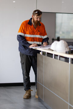 Male worker writing on the paper on the desk in the office.