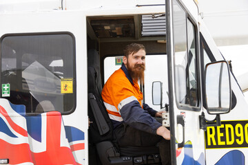 worker in high visibility clothing seated on the driver's seat of crane truck
