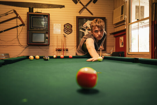 Teenage male playing 8 ball pool on billiard table in Australian pub