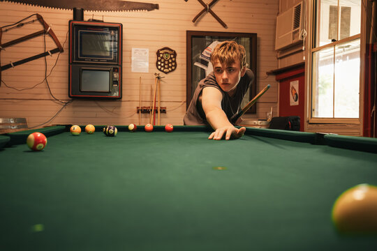 Teenage male playing 8 ball pool on billiard table in Australian pub