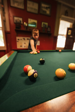 Teenage male playing 8 ball pool on billiard table in Australian pub