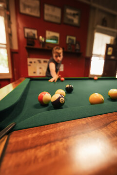 Teenage male playing 8 ball pool on billiard table in Australian pub