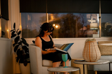Woman reading book in cosy, dimly lit living room with serene evening ambiance