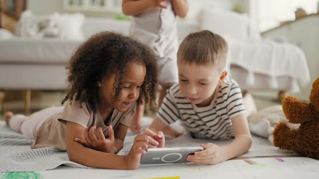 Children with smartphone, little five-years kids playing games in mobile phone. African American girl and Caucasian boy, diversity, internet addiction, modern kids over using mobile gadgets and apps