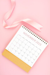 November 2025 desk calendar with pink ribbon.