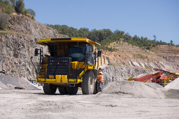 Man in high visibility clothes checking the sides of the dump truck.
