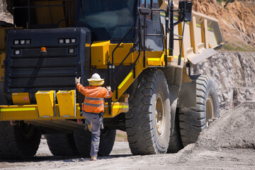 Man in high visibility clothes climbing up the dump truck.