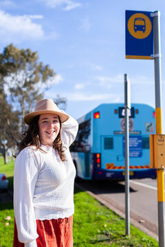 Young woman smiling beside public transport bus stop sign
