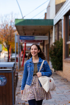 Young lady walking down street of country town in winter carrying bag