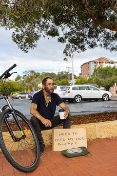 desperate man sitting with sign asking for help to feed his kids