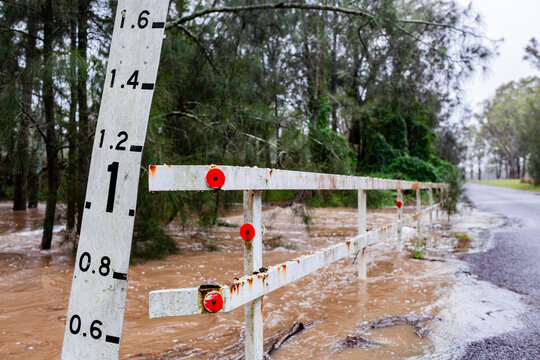 Depth meter beside bridge over creek that is almost underwater in flood