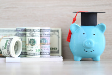 Graduation hat on piggy and banknotes on wooden background, Saving money for education concept