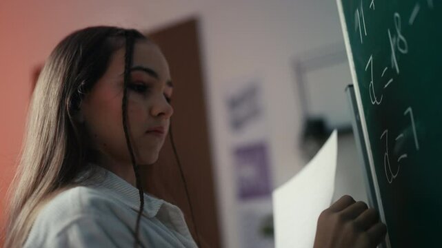 Schoolgirl writes equations on the chalkboard, part of the education process