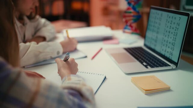 Two teenage girls use a laptop to write a test during a math lesson at school
