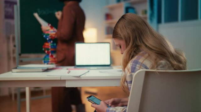 Schoolgirl texts on phone during lesson, prompting the teacher to make a remark