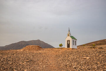 Small white wooden chapel in a monotonous rocky volcanic landscape. Church at sunrise. Twilight,...