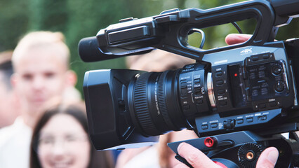 Videographer using a professional camcorder is recording group of students on their first school day
