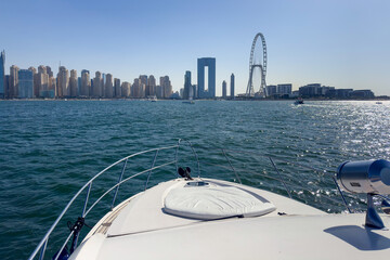 Luxury Dubai Marina skyscrapers, boat and promenade in beautiful summer day, Dubai, United Arab Emirates