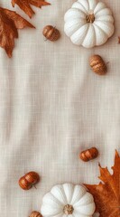 Fototapeta premium A light beige tablecloth with white pumpkins, acorns, and orange leaves on the sides of the cloth. 