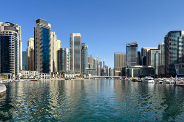 Luxury Dubai Marina skyscrapers, boat and promenade in beautiful summer day, Dubai, United Arab...