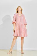 Stylish woman wearing a casual pink striped short summer dress and transparent heels