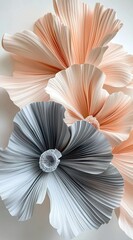 Gigantic pleated flowers made of paper, in a peach and grey color palette, against a white background