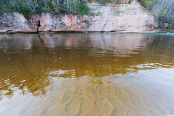 Crystal-clear river in Latvia. Sandy bottom, steep bank, and autumn colors.