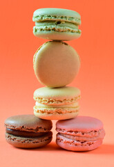 Close up. Macarons stacked, isolated, on orange background and vertical shot.