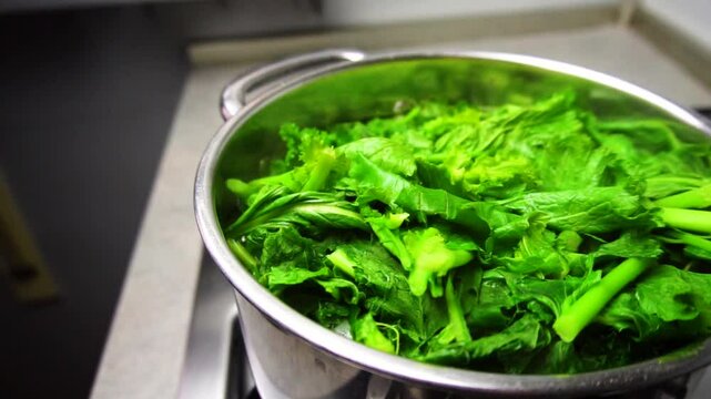Boiling turnip greens with the intent of cooking them for the apulian dish "orecchiette con le cime di rape". Slow motion with bubbles coming from the water and smoke.