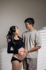 Naklejka premium Happy loving couple enjoying moments of pregnancy, finger show heart shape on the tummy