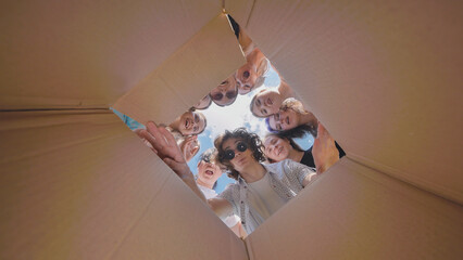 High school students peering into a large cardboard box, showing excitement and amazement over summer vacation