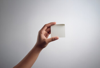 A hand holds a blank white card in front of a plain white background.