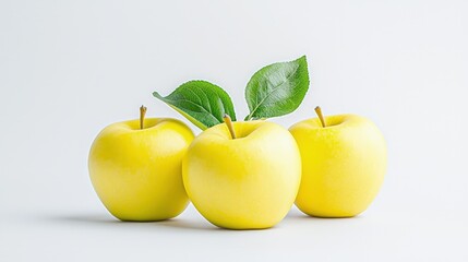 Three ripe yellow apples with green leaves on white background.