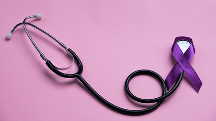 Purple epilepsy awareness ribbon with stethoscope and copy space on a pink background. World epilepsy day. Purple Day.
