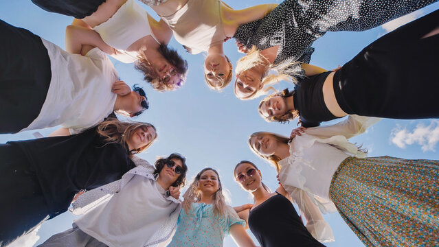 Group of high school students forming a circle, embracing each other, symbolizing unity and friendship during summer break