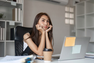 Stressed Businesswoman at Office Desk with Laptop and Coffee, Feeling Overwhelmed and Tired from Workload in Modern Workspace