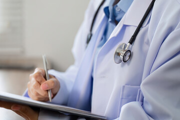 Doctor Recording Patient's Symptoms in Medical Office with Stethoscope and Clipboard for Healthcare...