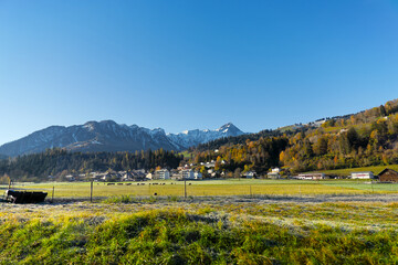 Scenic view of rural landscape in the Swiss Alps with Swiss village of Cazis in the background on a sunny autumn morning. Photo taken November 15th, 2024, Cazis, Switzerland.