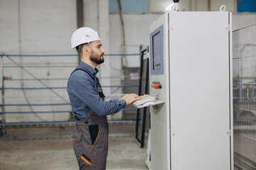 Factory worker operating industrial machinery for aluminum and pvc windows and doors production